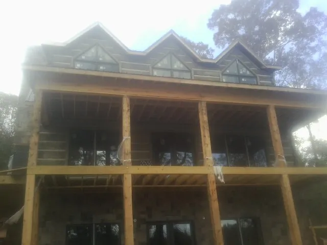 Dormers and porch framing on a large log home under construction — Roof Coating work by our crew in Foster